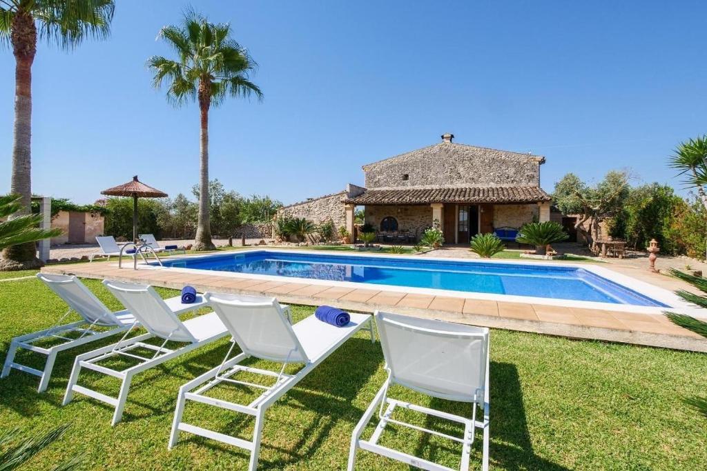 a group of lawn chairs in front of a swimming pool at Finca Fonoll in Santa Margalida