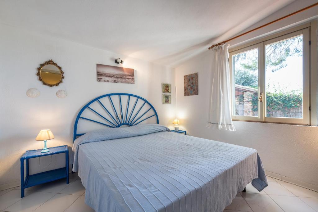 a bedroom with a blue bed and a window at Villetta Simius in Villasimius