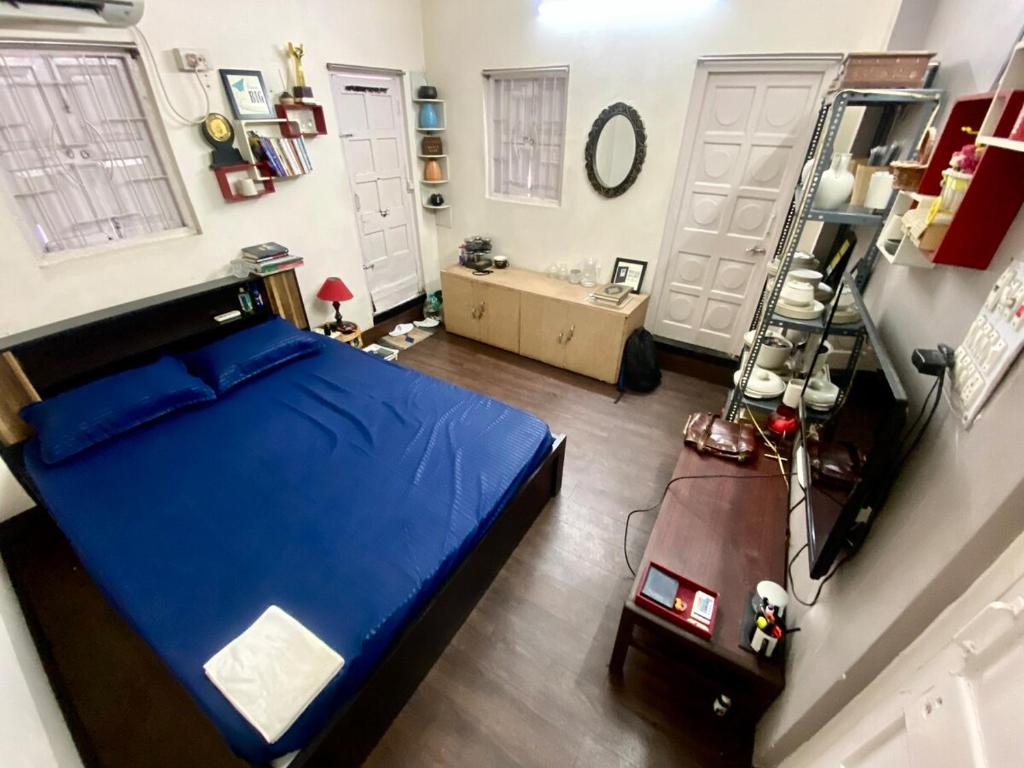 a bedroom with a large blue bed and two white doors at Large room with terrace in Kolkata