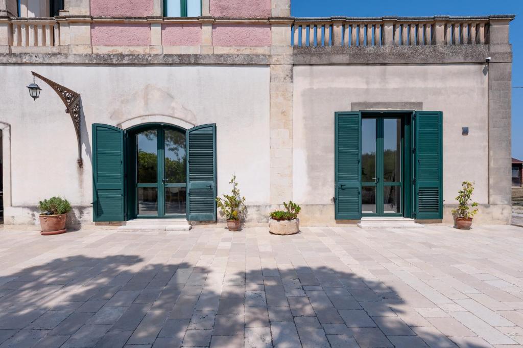 a building with green shutters on a patio at Villa Minioti Apartment A in Arnesano