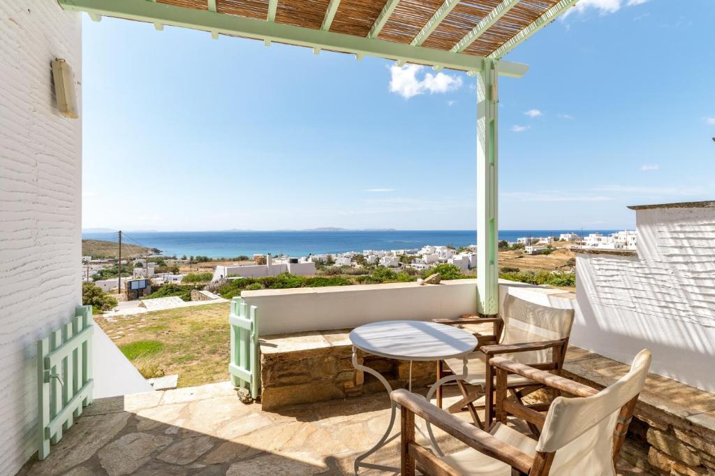 a patio with a table and chairs and a view of the ocean at Anemologio 102 Tinos in Agios Ioannis