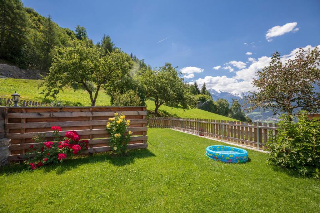 a yard with a fence and flowers and a frisbee at Vernalhof Apt Sunnaseit in Sluderno