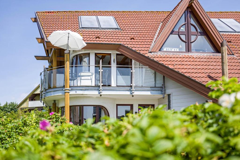 a house with a balcony with an umbrella at Moin Moin in Friedrichskoog-Spitze