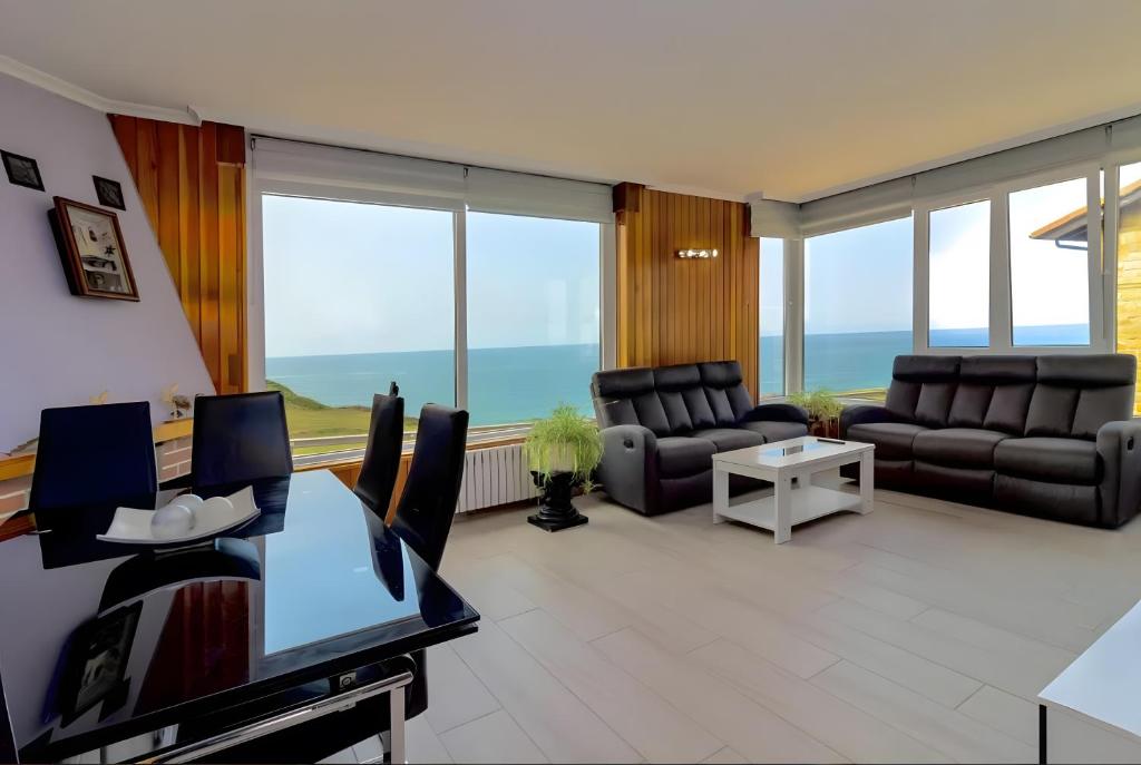a living room with leather furniture and large windows at Villa Laurana in Suances