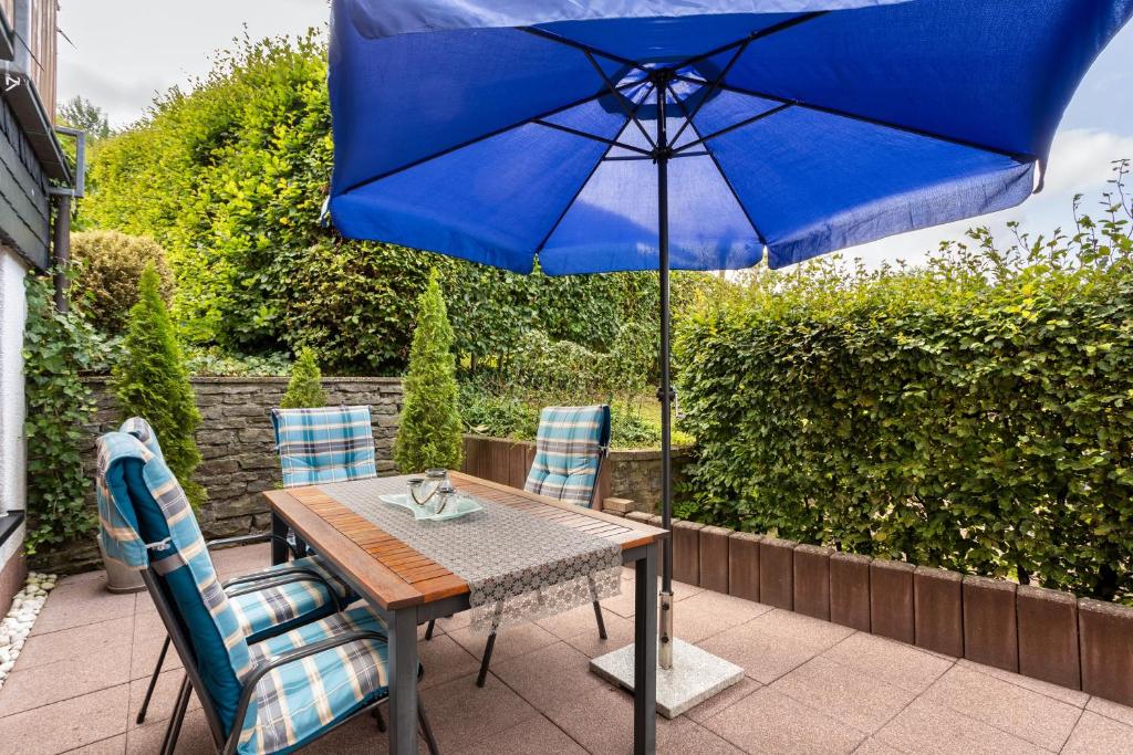 a table with a blue umbrella on a patio at Ferienwohnung Christa in Lennestadt