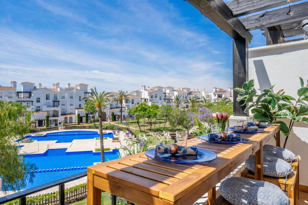 a wooden table on a balcony with a swimming pool at Casa Albatros - Poolside Retreat in Torre-Pacheco