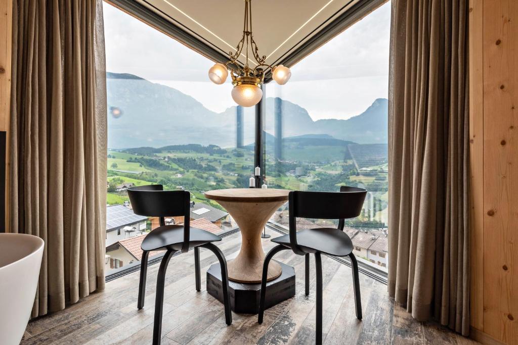 a room with a table and chairs in front of a large window at Aumia Apartment Diamant in Völs am Schlern