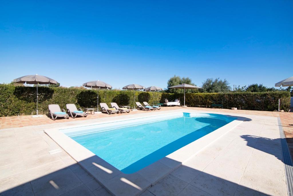 a pool with chairs and umbrellas next to a house at Villa Oliva Al iii in Moncarapacho