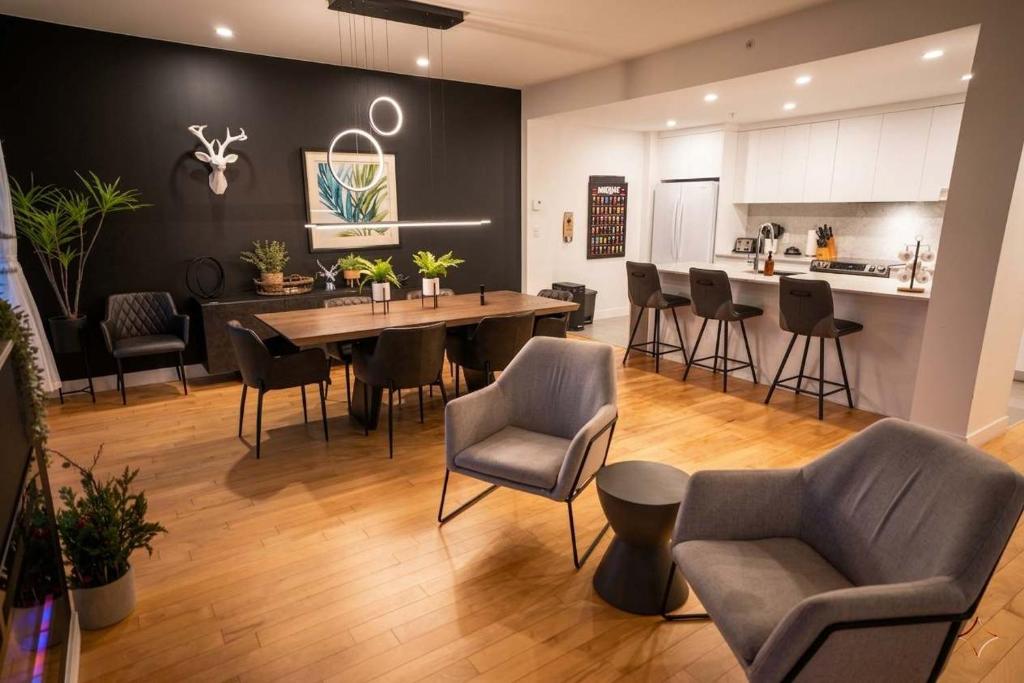 a living room with a table and chairs and a kitchen at 206 - Bright Modern Condo - Pool and River View in Baie-Saint-Paul