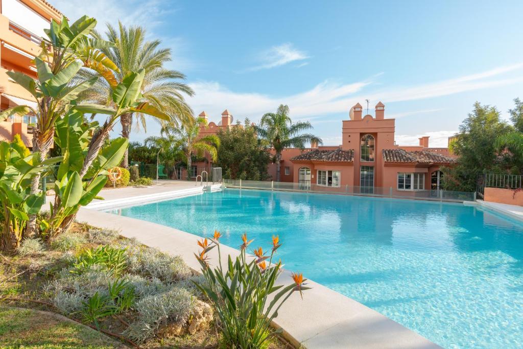 a swimming pool in front of a house with palm trees at Fuengirola Hills with Seaview in Fuengirola
