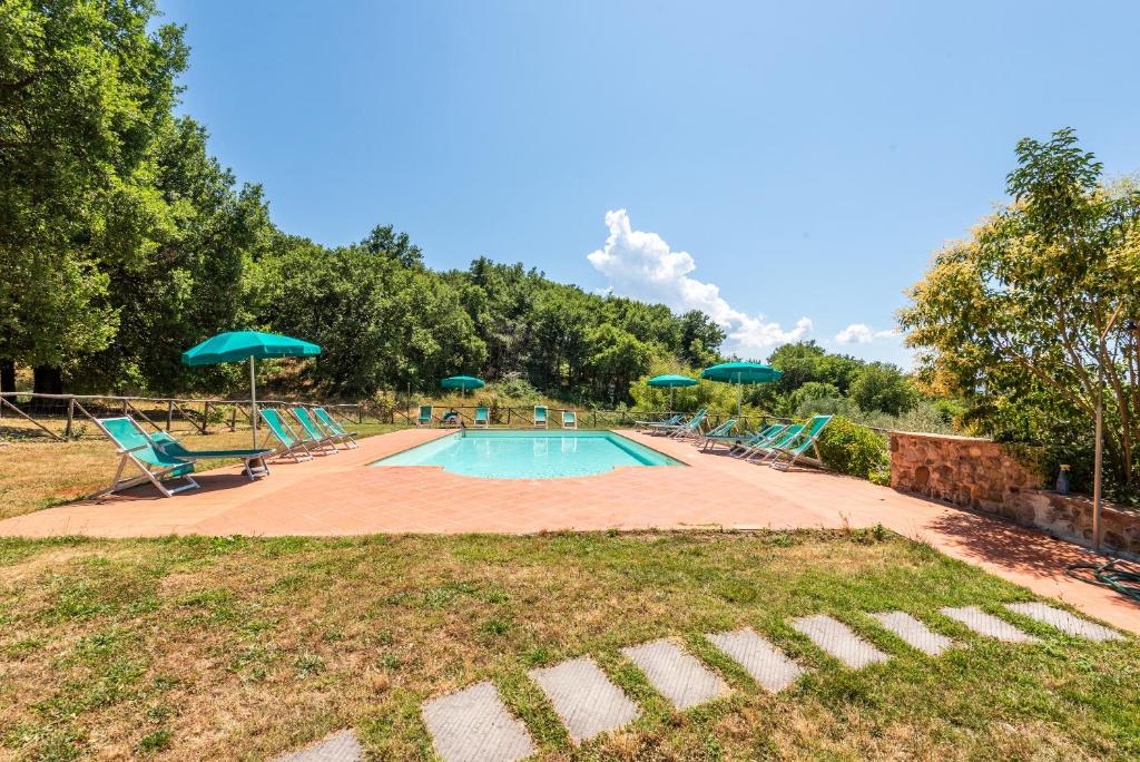a swimming pool with chairs and umbrellas at Agriturismo Paugnano in Radicondoli