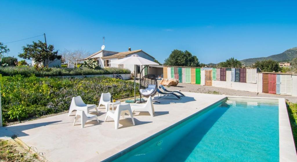 a group of white chairs and a swimming pool at Finca Sa Real in Cala Millor