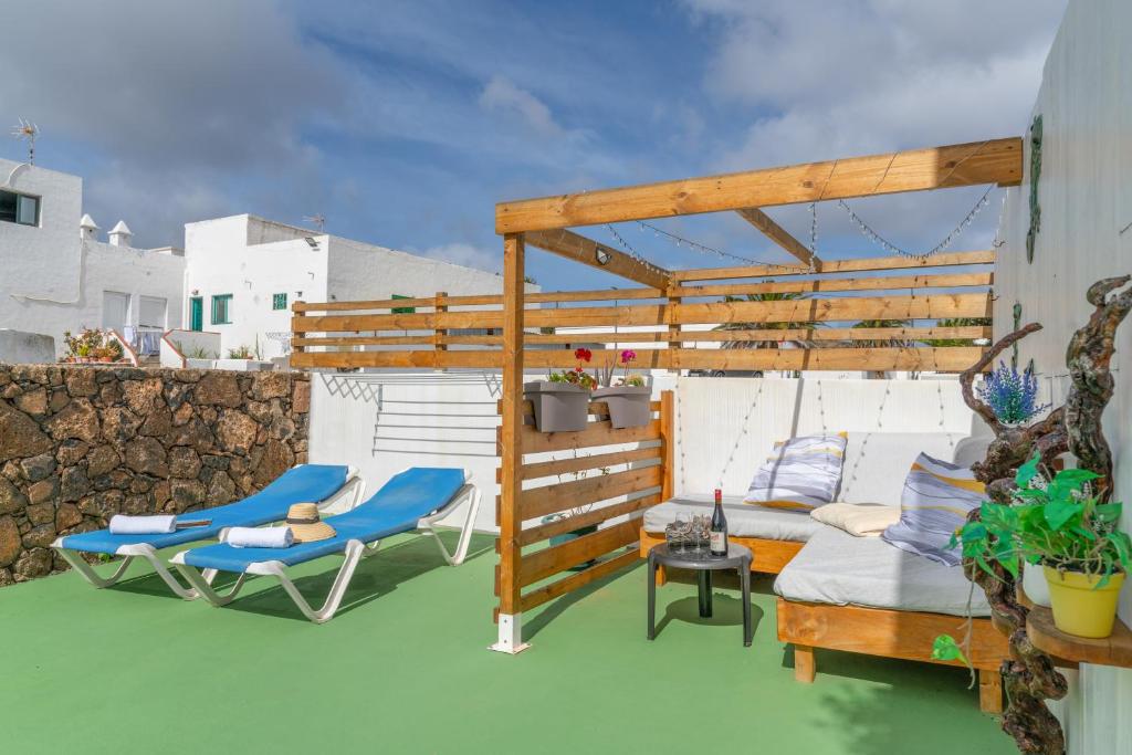 a deck with chairs and a bed and a pergola at Apartamento Liz in Tías