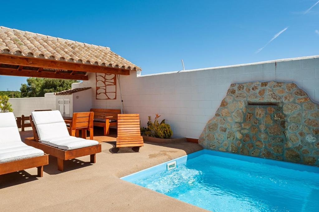 a patio with a pool and chairs and a fireplace at Casa - 2 Mar y Sombra in Barbate