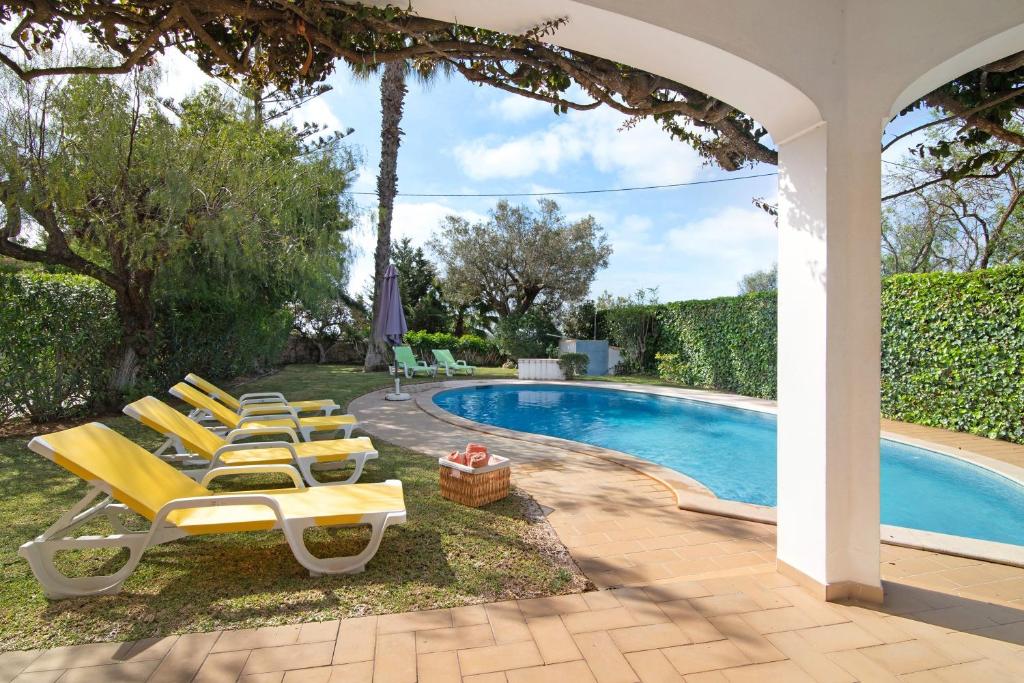a group of yellow lounge chairs next to a swimming pool at Casa da Oliveira in Loulé
