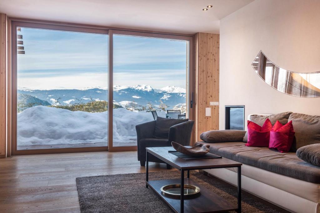 a living room with a couch and a large window at Aura Chalets - Nr 3 in Castelrotto
