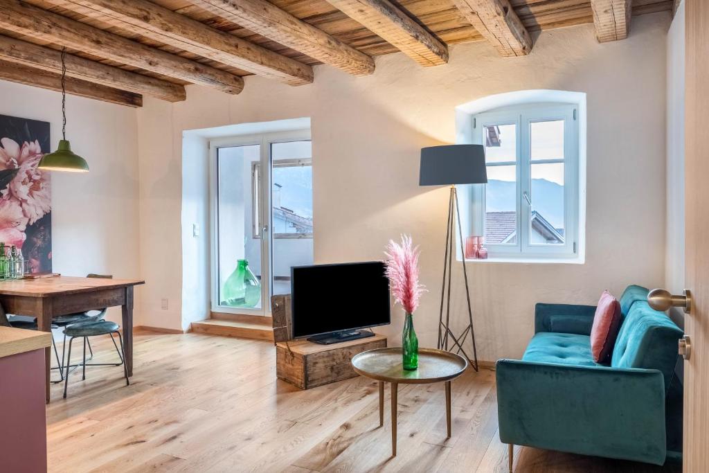 a living room with a blue couch and a tv at Eichhof Apartment Thymian in Termeno