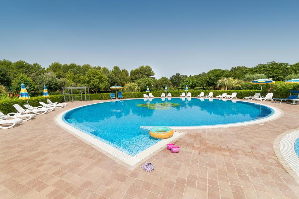 a large swimming pool with chairs and umbrellas at Il Girasole - Cappero in Venturina Terme