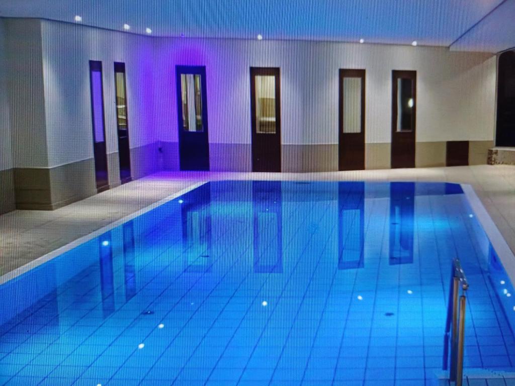 a large swimming pool in a building with purple lighting at Apartementhaus Lord Nelson in Cuxhaven