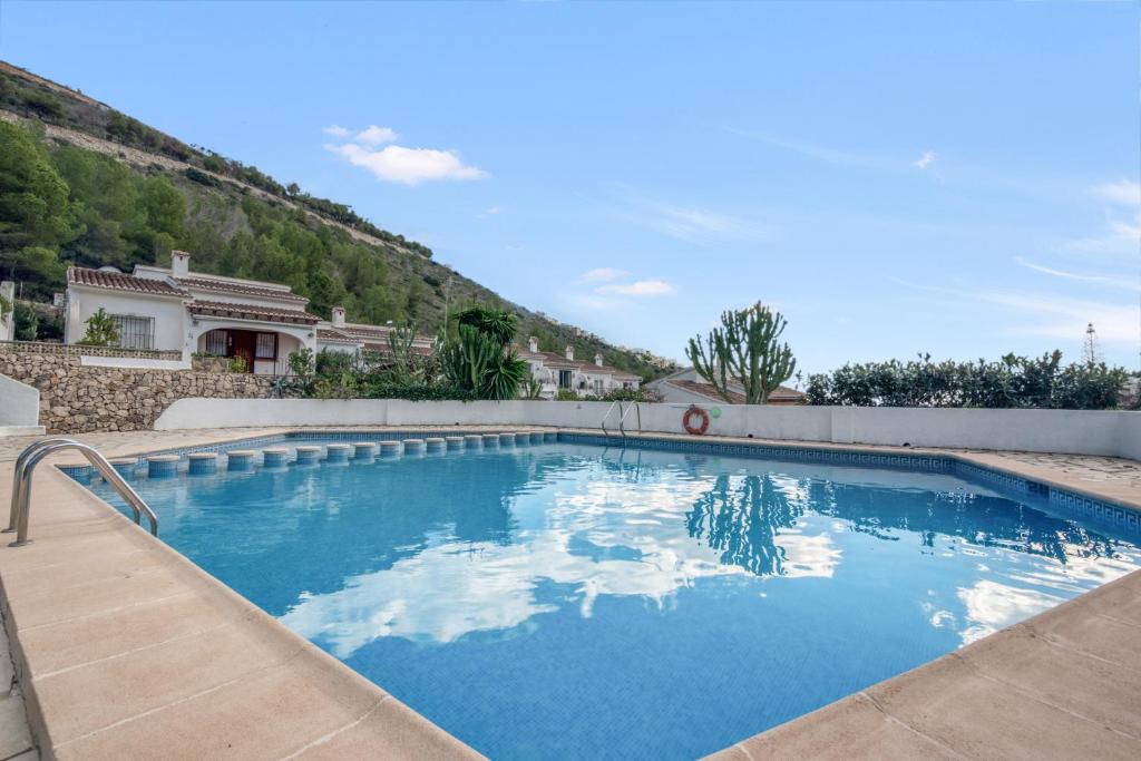 a swimming pool with blue water in front of a house at Casa Julieta in Benitachell