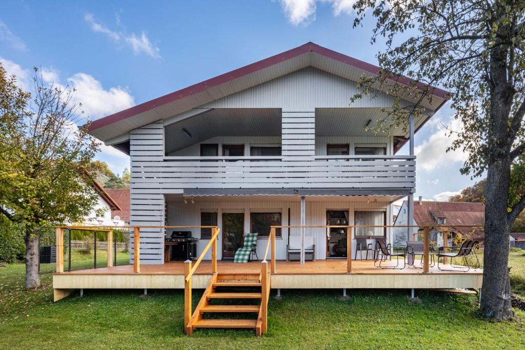 a house with a deck and two wooden stairs at Ferienwohnung an der Lauter in Indelhausen