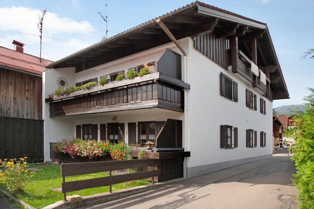a white building with a balcony with plants on it at Ferienwohnung Reindler in Fischen
