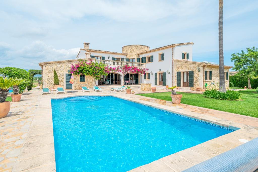 a villa with a swimming pool in front of a house at Casa Verde in Sa Pobla