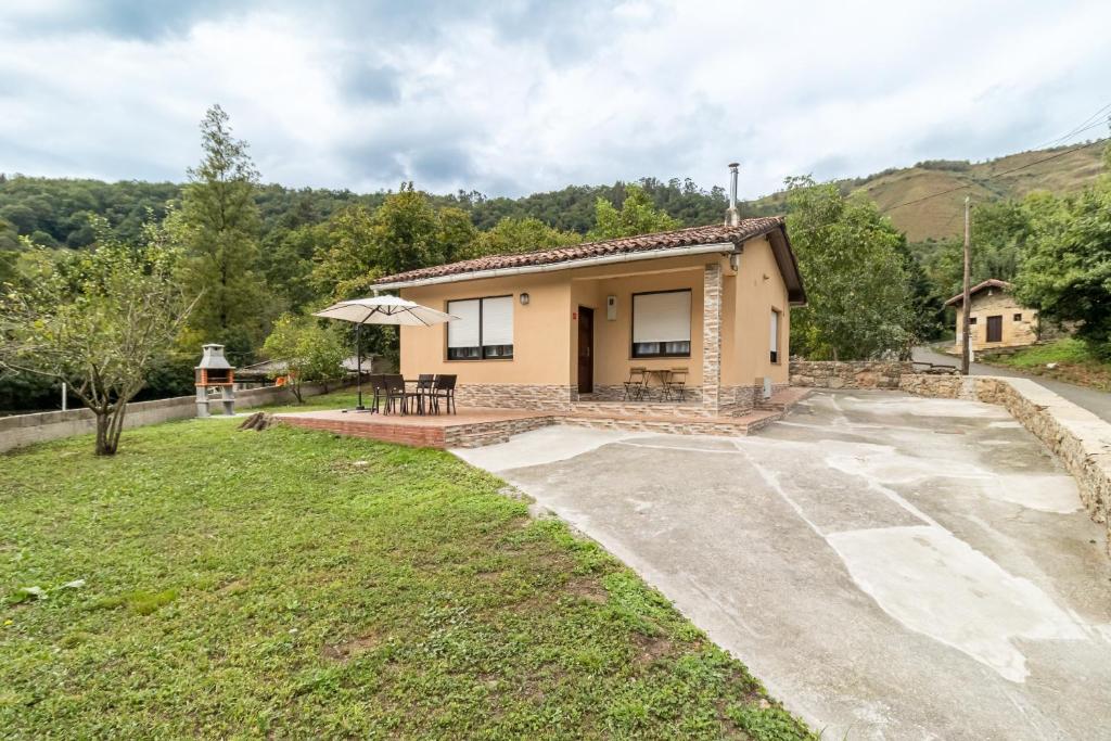 a small house with a table and an umbrella at Susurros de río in Ocejo