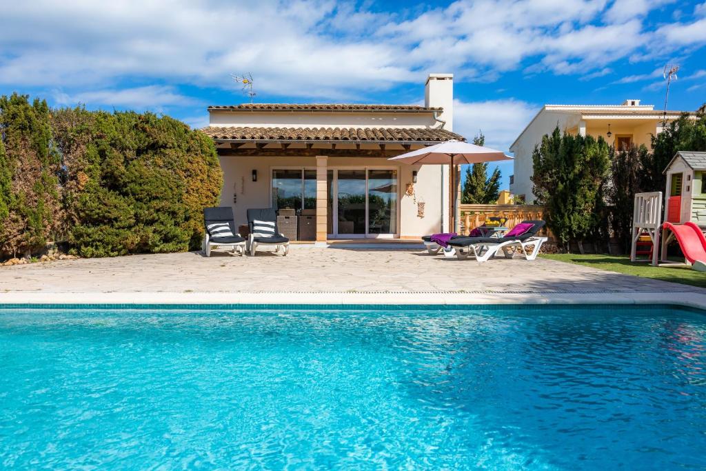 a swimming pool with two chairs and a house at Casa Arturo in Sa Coma