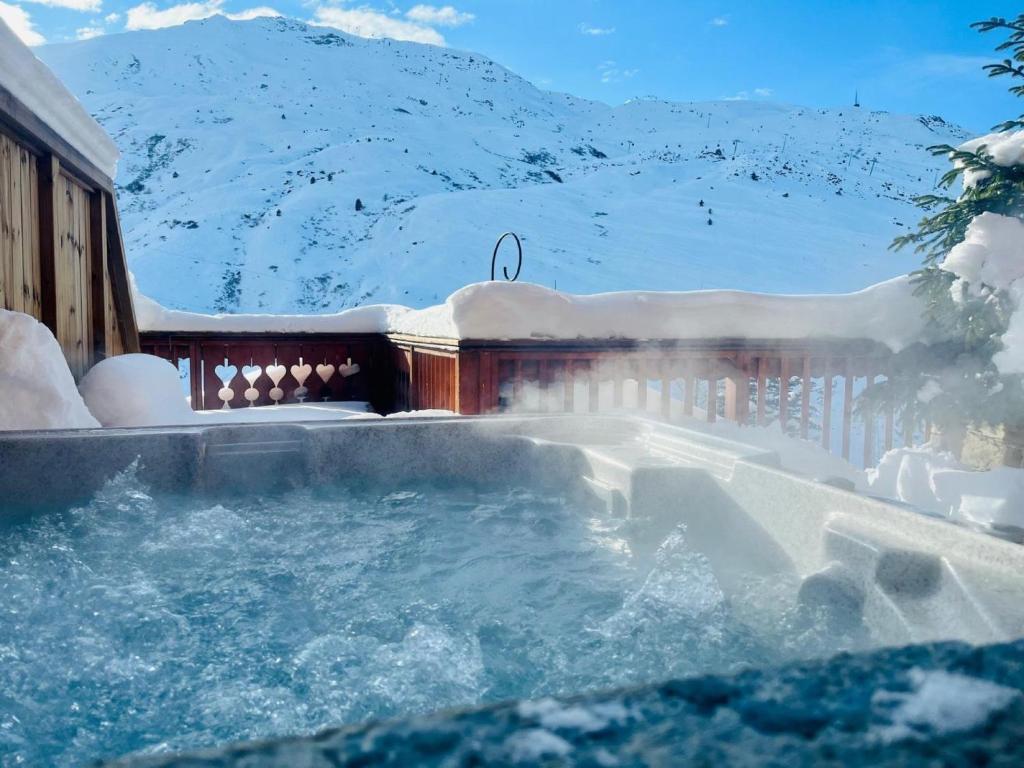 a hot tub covered in snow next to a building at Chalet Delphine Luxe, Ski aux pieds in Les Bruyères