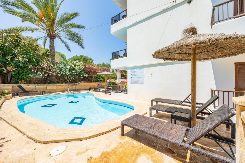 a swimming pool with an umbrella and two chairs and a table at Gran Sol Family 4 in Felanitx