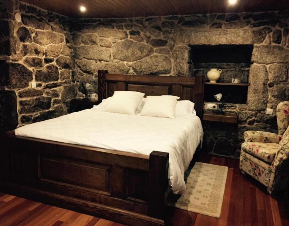 a bedroom with a bed and a stone wall at O Cantón in La Bola