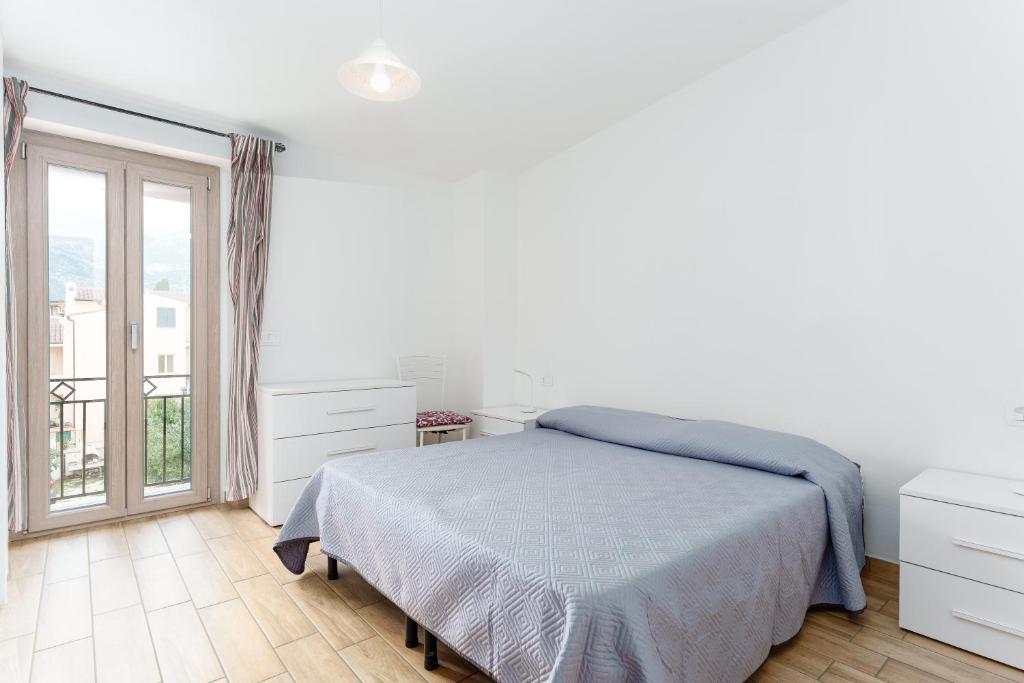 a white bedroom with a bed and a window at Enjoy The Silence Flat in Orosei