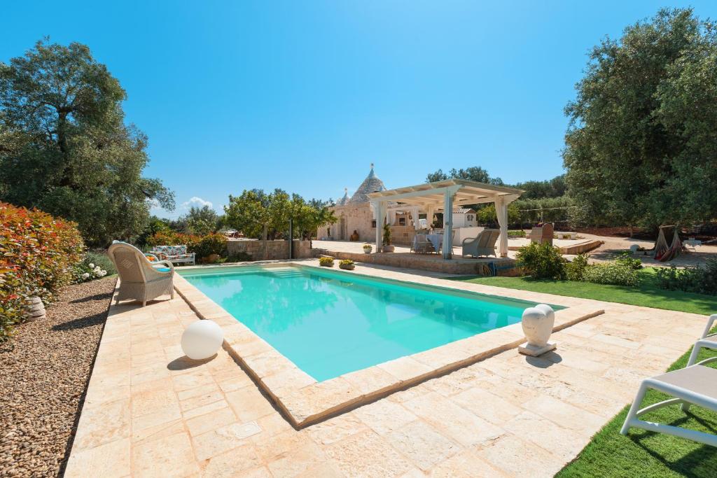 a swimming pool in a yard with chairs and a house at Trullo Milù in San Michele Salentino