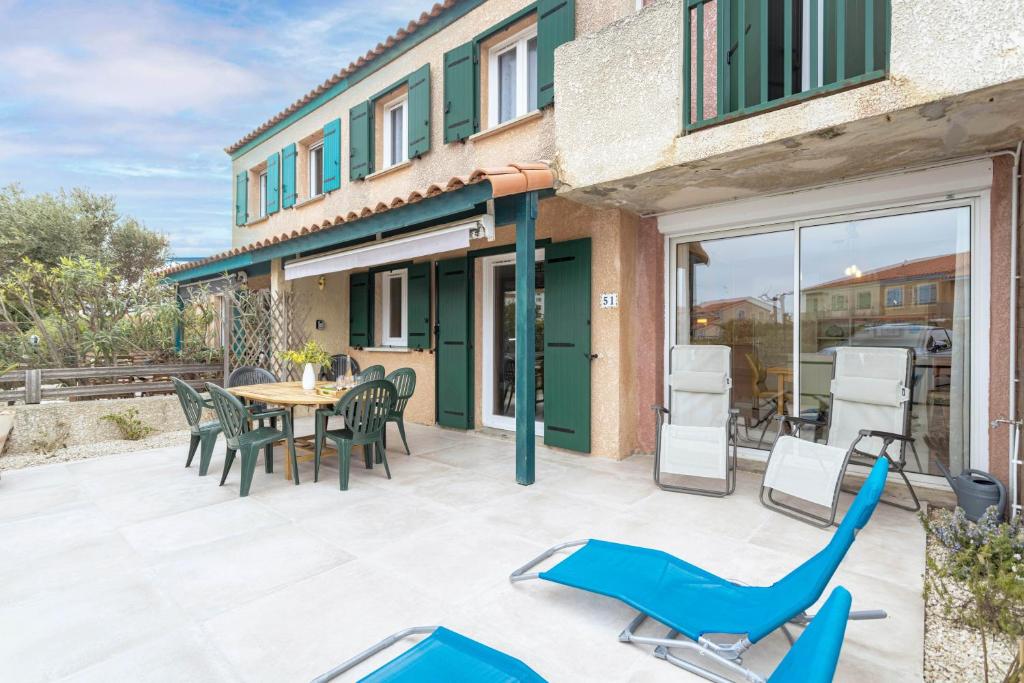 a patio with blue chairs and a table and chairs at Maison Goéland in Le Barcarès