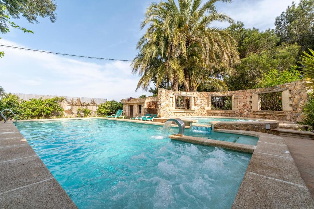 an outdoor swimming pool with a stone building and trees at La Carrasca in Catral