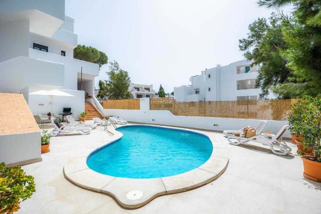 a swimming pool in the middle of a patio with lounge chairs at White suites 2 in Cala d´Or