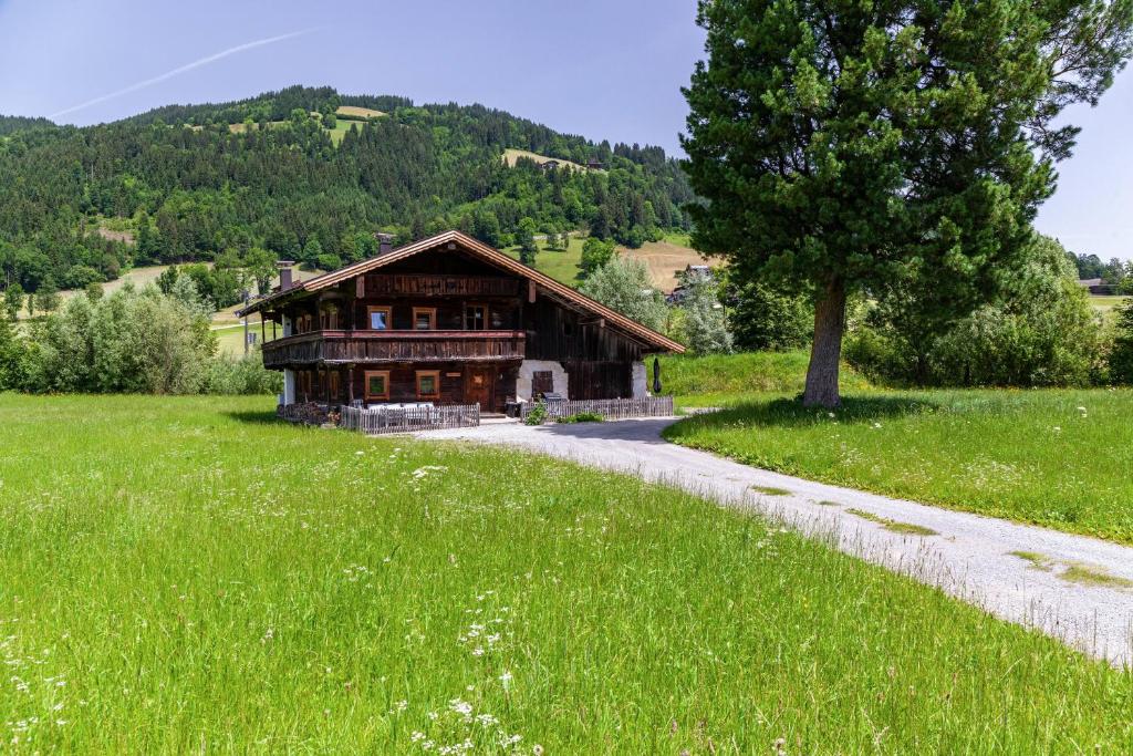 a house in a field with a tree and a road at The Farm in Westendorf