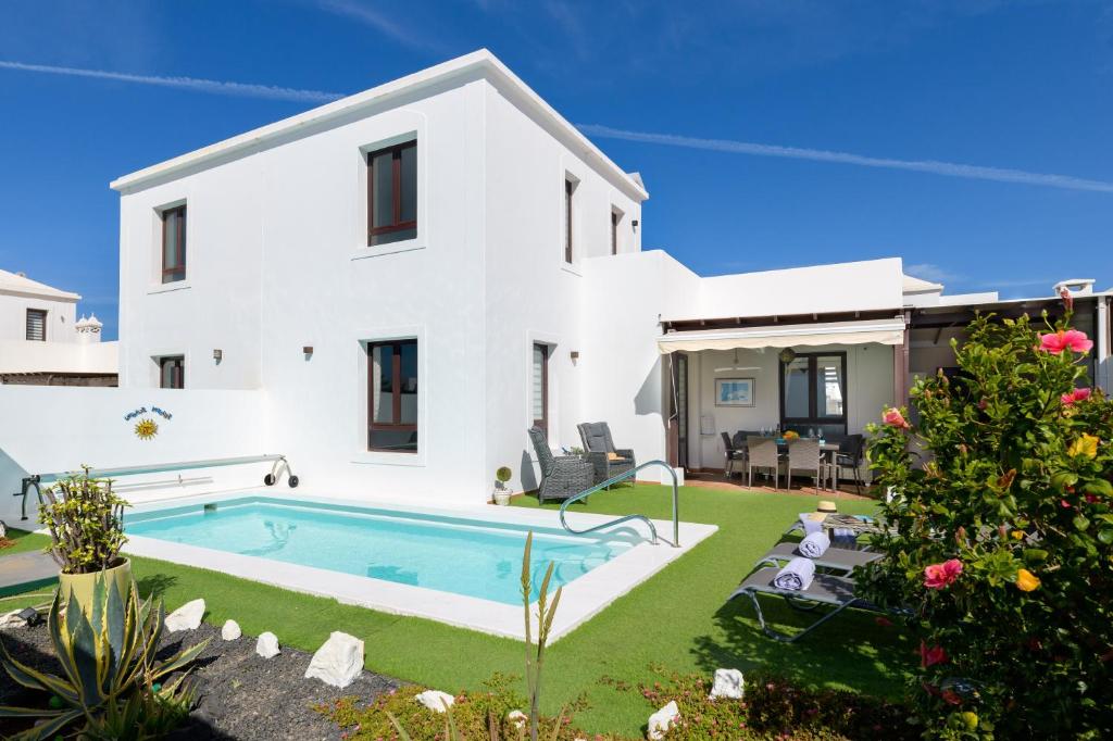 a white house with a swimming pool and a yard at Villa Petruca in Playa Blanca
