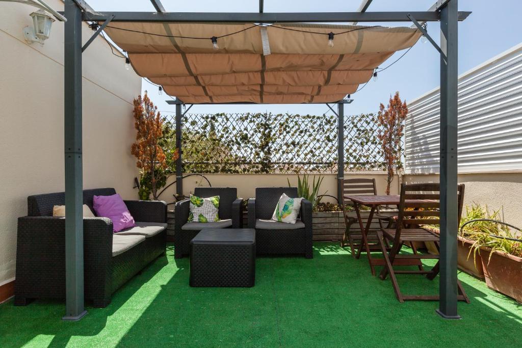 a pergola with couches and a table and chairs at La Cantonada in Sant Pere de Ribes