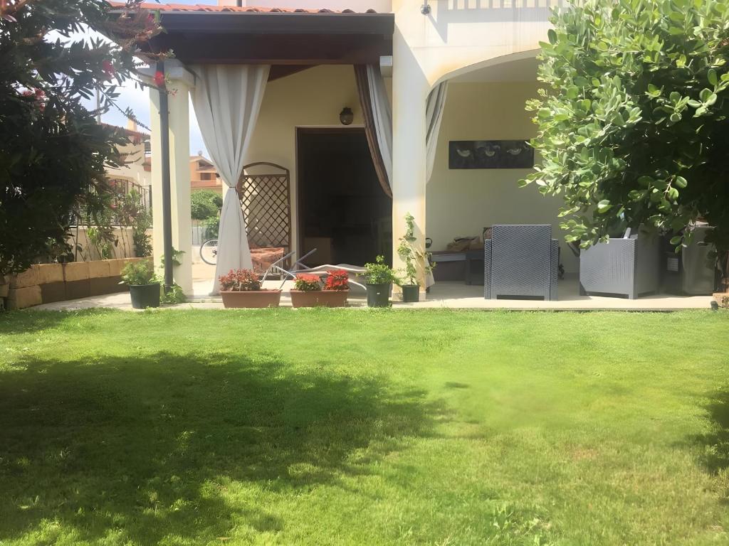 a yard with green grass and a house at Villa Fiorita in Budoni