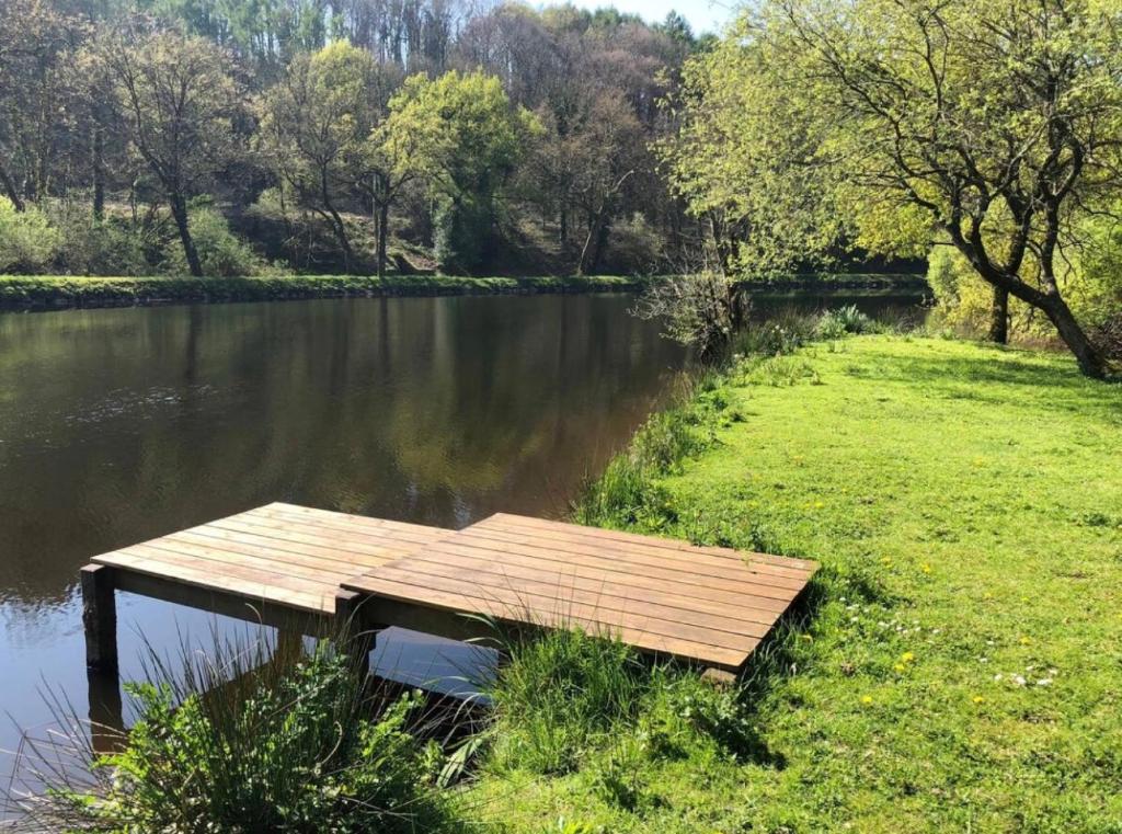 a wooden dock sitting on the side of a river at Les gîtes Bretons in Bieuzy-les Eaux