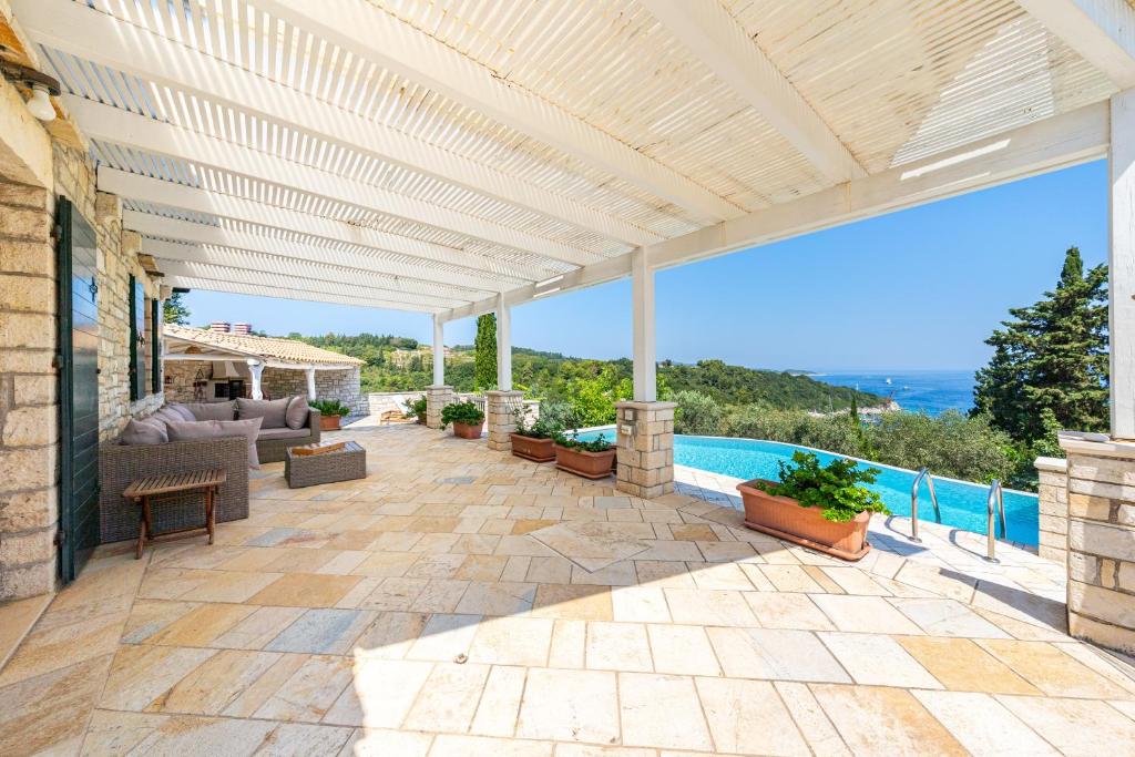 an outdoor patio with a pergola and a pool at Villa Iremia Antipaxos in Antipaxos