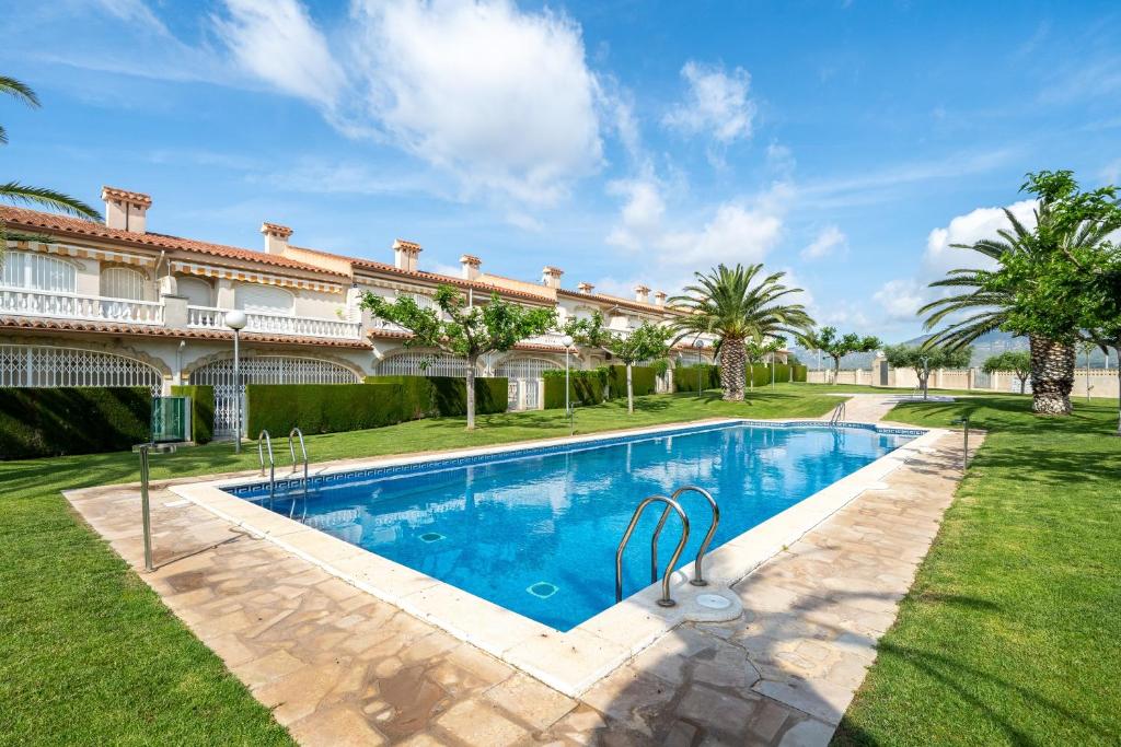 a swimming pool in the yard of a house with palm trees at Montserrat in Miami Platja