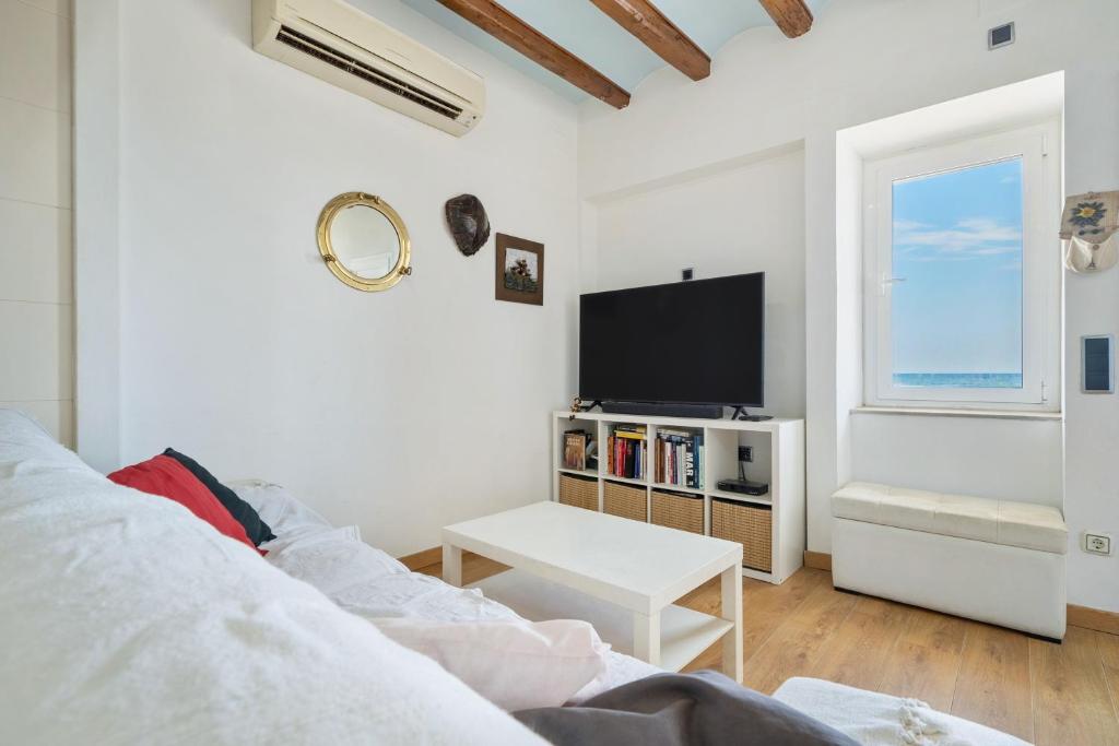 a white living room with a tv and a couch at Voramar in Torredembarra