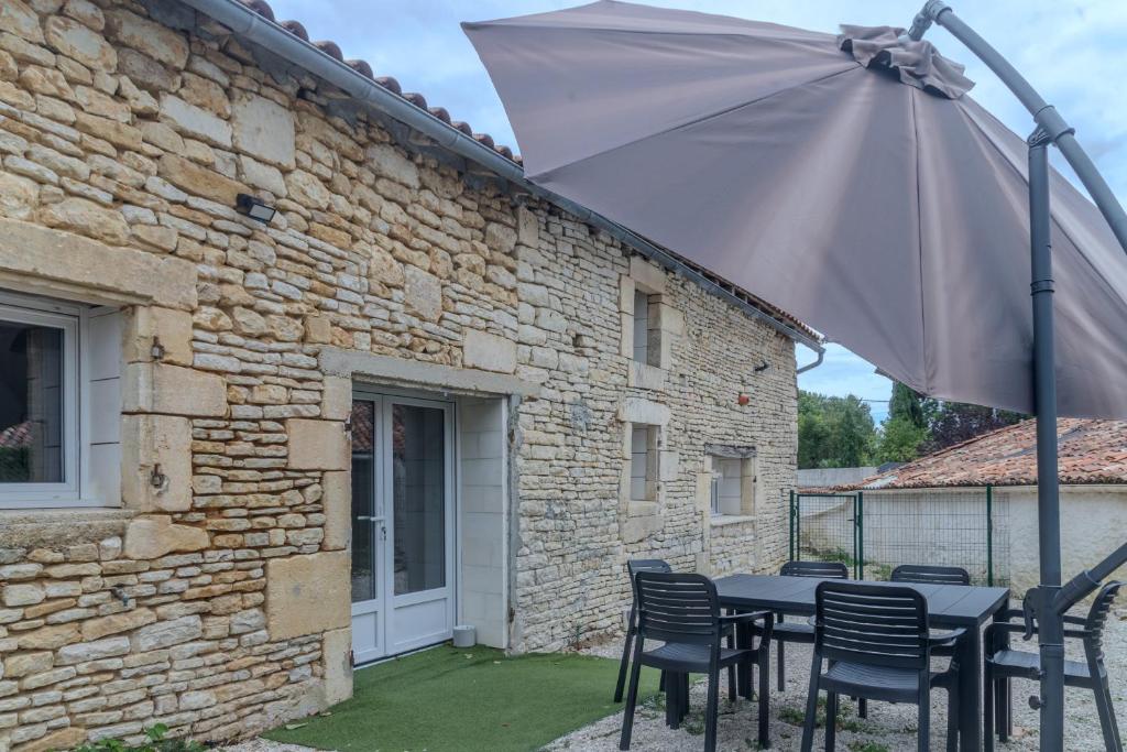 a table with chairs and an umbrella in front of a building at Gite Berclois in Bercloux