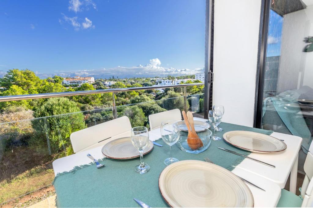 a table with plates and wine glasses on a balcony at Sa Perdiu 14 Menorca in Cala Santandria