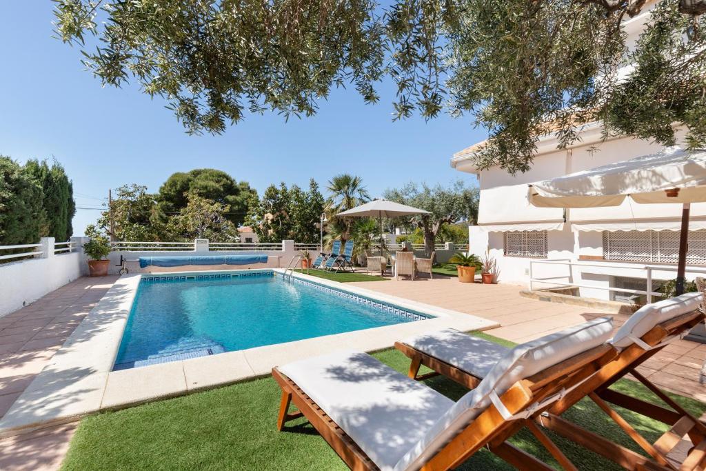 a swimming pool with two lawn chairs and an umbrella at Semisótano in Cartagena