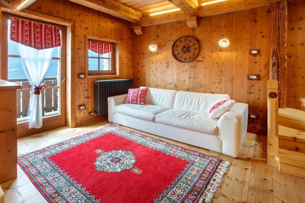 a living room with a white couch and a red rug at Chalet Del Cuore in Valdisotto