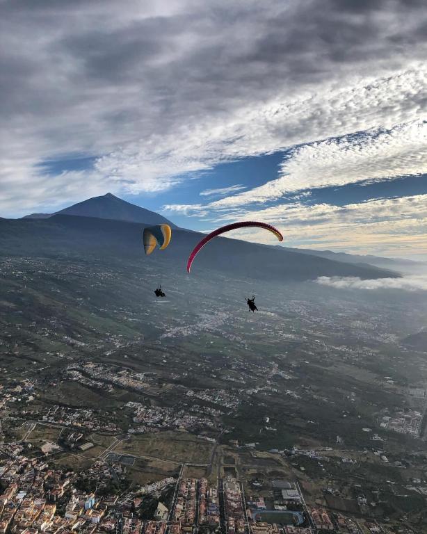 two people flying kites in the sky over a city at Cala Sunrise in Los Realejos